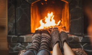 A couple warming their feet around a fireplace