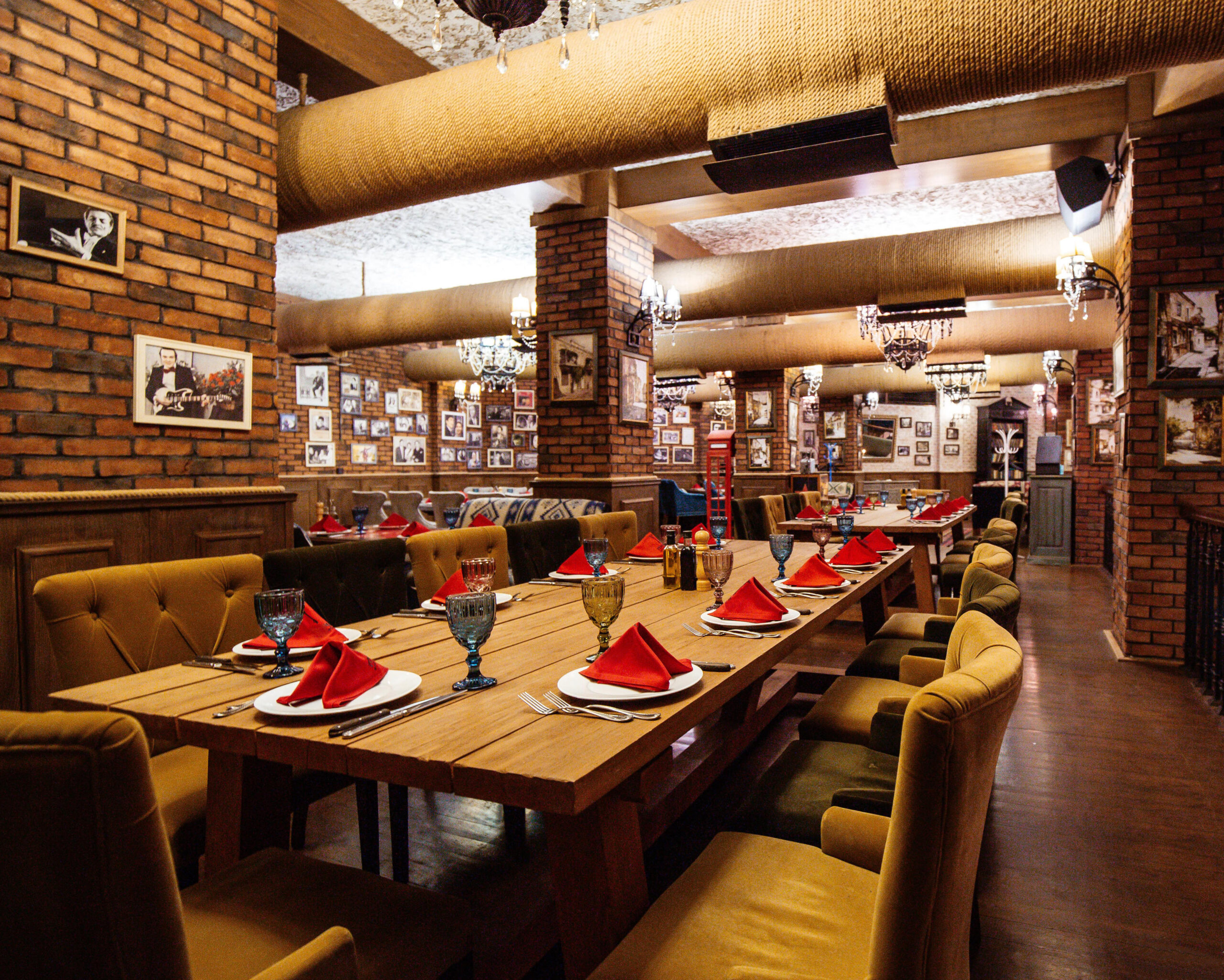 Restaurant hall with red brick walls wooden tables pipes ceiling scaled